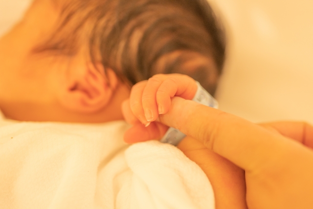 生まれたての赤ちゃんが大人の指を握る写真